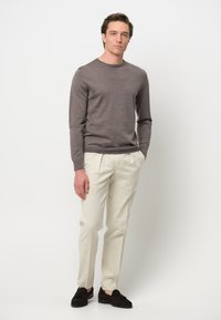 Grauer langärmeliger Pullover, cremefarbene tailored Hose und dunkle Wildleder-Lederschuhe. Glatte Textur, klassischer Schnitt, schlichtes Design, keine sichtbaren Muster.