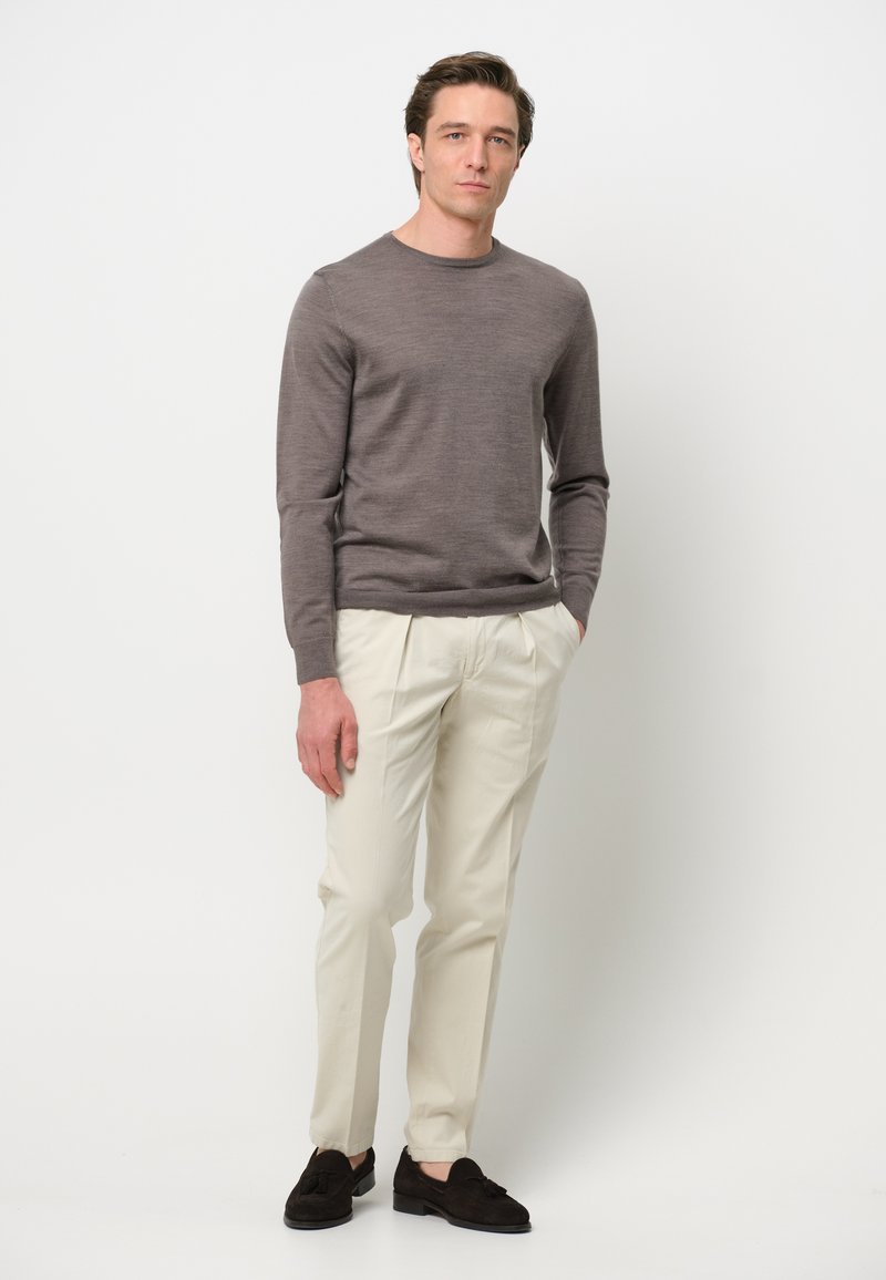 Grauer langärmeliger Pullover, cremefarbene tailored Hose und dunkle Wildleder-Lederschuhe. Glatte Textur, klassischer Schnitt, schlichtes Design, keine sichtbaren Muster.