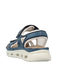 Blå lädersandal med en texturerad beige gummisula, justerbara remmar, öppen design och kontrasterande krämfärgade detaljer.