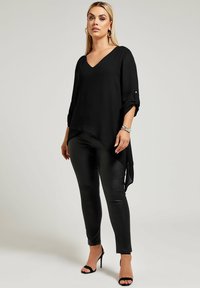 Top nero a trama con scollo a V e maniche a tre quarti, abbinato a pantaloni in finta pelle nera e tacchi aperti neri.