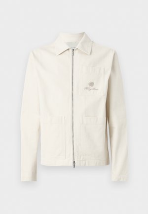 Veste blanche cassée zippée avec col, trois poches plaquées à l'avant et logo brodé discret sur la poche poitrine gauche.