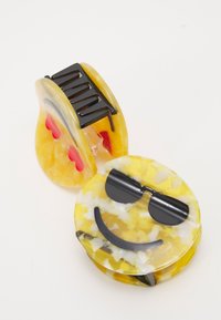 Clip de cabelo em forma de emoji em resina amarela e branca com mármores, apresentando óculos escuros pretos e detalhes. Textura suave com um design divertido.