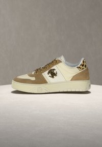 Μπεζ και λευκό αθλητικό παπούτσι χαμηλού προφίλ με σουέτ λεπτομέρειες, γιακά με λεοπάρ σχέδιο και κορδόνια, και διακοσμητικό μεταλλικό λογότυπο στο πλάι.