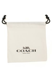 Sac en toile à cordon crème avec quincaillerie noire. Présente le logo "COACH NEW YORK" et un graphique équestre en noir. Texture lisse.