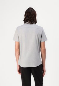 Grijs T-shirt met korte mouwen van een geweven stof, met een rechte zoom en subtiele schoudernaden. De achterkant toont een glad design zonder logo's.