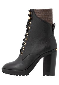 Stivaletto in pelle nera con occhielli dorati, tomaia in fibra tessile marrone e tacco alto chunky nero. Progettato con una suola robusta per una migliore aderenza.