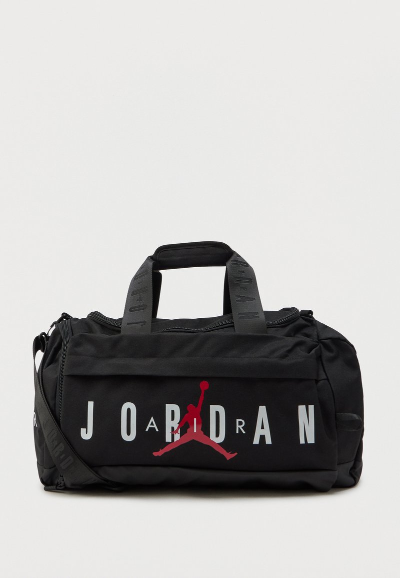 Svart duffelbag med fremtredende "JORDAN"-logo, rød Jumpman-grafikk og nylonmateriale. Har doble håndtak og justerbar skulderreim.