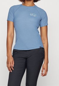 Světlomodrá košile s krátkým rukávem, kulatým výstřihem a raglánovými rukávy. Na horní části hrudi je barevné logo. Měkká, hladká tkanina.