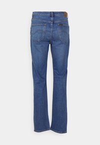 Jean en denim bleu avec une coupe droite, style cinq poches, coutures contrastantes et une étiquette en cuir marron sur la ceinture arrière.