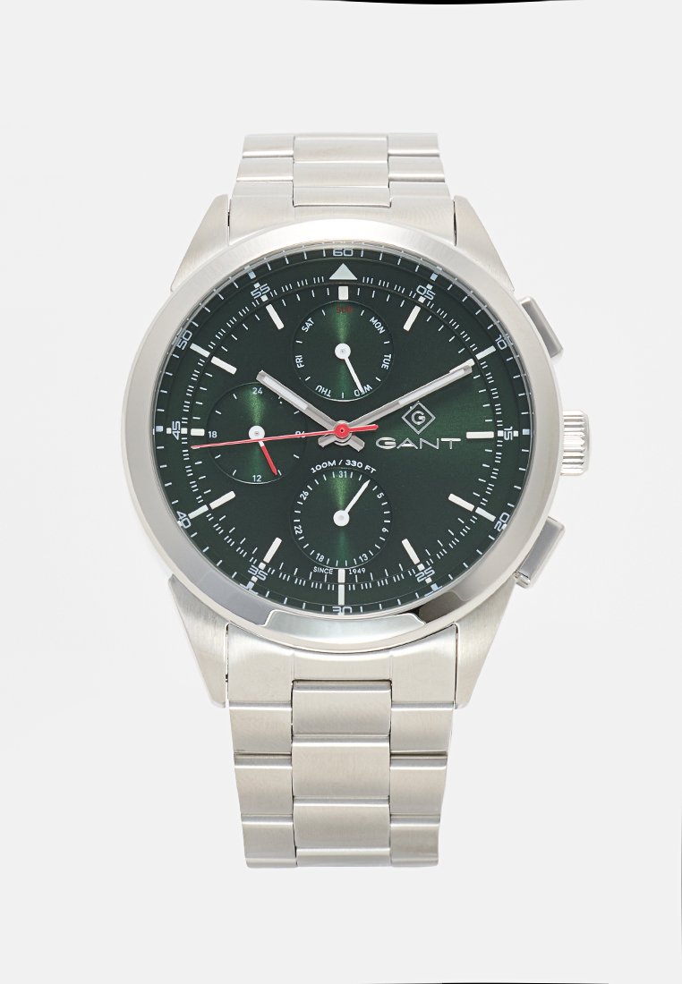 Reloj cronógrafo de metal con esfera verde, caja de tono plateado y pulsera plateada. Cuenta con tres subesferas y detalles en rojo. Resistente al agua hasta 100 m.