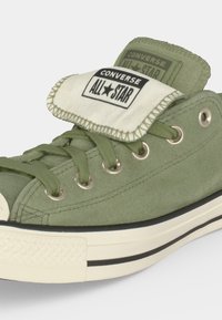 Зелен нисък Converse All Star кец с бяла гумена подметка и сгънат език, показващ логото.