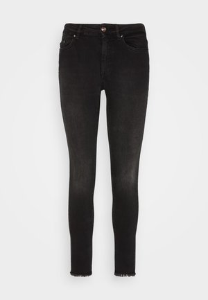 Des jeans skinny en denim noir présentent une silhouette ajustée, un léger effet usé au bas, et un design classique à cinq poches avec un bouton en métal.