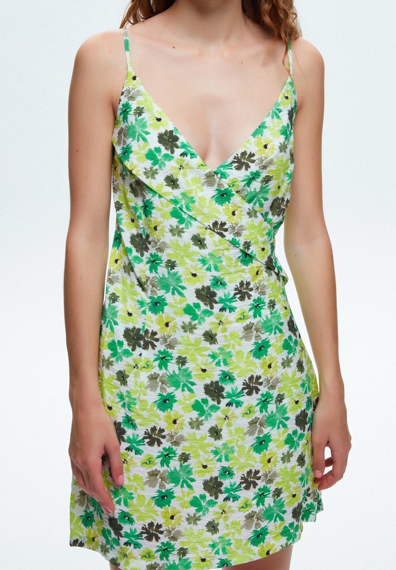 Robe à fleurs avec bretelles spaghetti aux motifs jaunes, verts et marron ; tissu léger avec un design portefeuille et un décolleté en V.