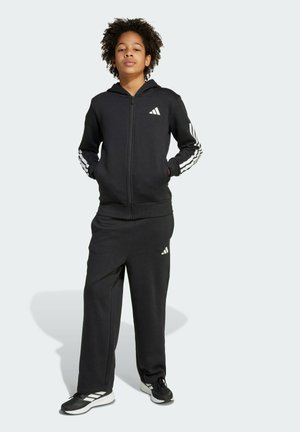 Sort zip-up hoodie med hvid Adidas-logo og tre striber på ærmerne, parret med matchende sorte sweatpants med logo på låret.