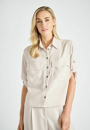 Beige shirt met korte mouwen en een kraag, voorzien van twee voorschildpocketen en een knoopsluiting. Glad stof met een ontspannen pasvorm.