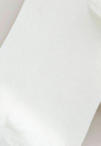 Fehér pamut zokni sima textúrával és enyhe fényes felülettel, a tetején bordázott mandzsettával és varrás nélküli orr-résszel.