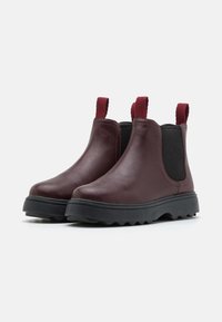 Burgunderfärgade läder Chelsea-boots med elastiska sidopanels och tabbar på hälen. Kraftig svart sula med ett strukturerat mönster för bra grepp.