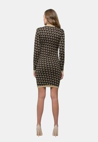 Abito in maglia nera con motivo di uccelli dorati, maniche lunghe e una forma aderente. Decorato con orlo dorato e polsini coordinati.