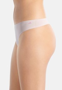 Roze naadloze stringondergoed met een gladde textuur en een minimalistisch ontwerp. Bevat een zachte, brede tailleband en subtiele branding aan de zijkant.