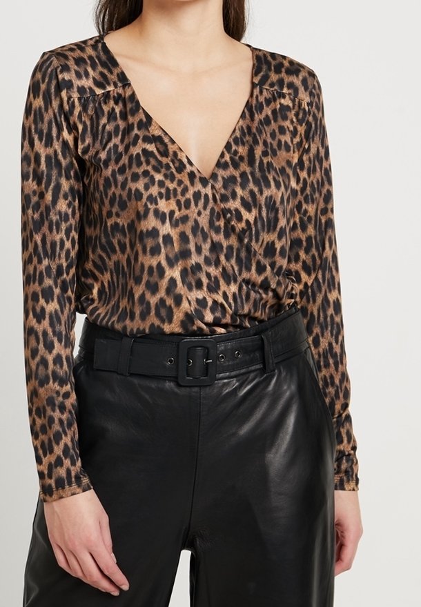 Lepelprint lange mouw top met een diepe V-halslijn, voorzien van een zachte stof en geraffineerde schouderdetails, gecombineerd met hoge zwarte leren broeken.