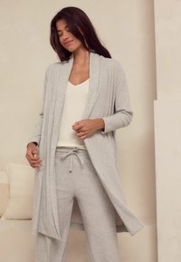 Lichtgrijze, geribbelde gebreide cardigan met open voorkant, lange mouwen en bijpassende broek met een elastische tailleband en trekkoord.