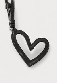 Black leather heart-shaped keychain with a cutout center, featuring contrasting stitching and a metal loop attachment for securing keys or accessories.