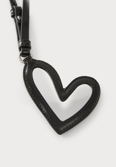 Porte-clés en cuir noir en forme de cœur avec un centre découpé, présentant des coutures contrastées et un attache en métal pour sécuriser les clés ou les accessoires.