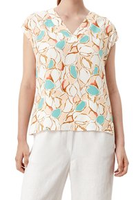 Haut à manches courtes avec col en V, en tissu léger, arborant un motif floral aux couleurs orange, bleu sarcelle et crème. Ourlet légèrement arrondi en bas.