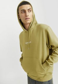 Olivgrüner Kapuzenpullover mit Kordelzugkapuze, vorderer Kängurutasche und weißem Logotext auf der Brust. Das Material ist weich und strukturiert.