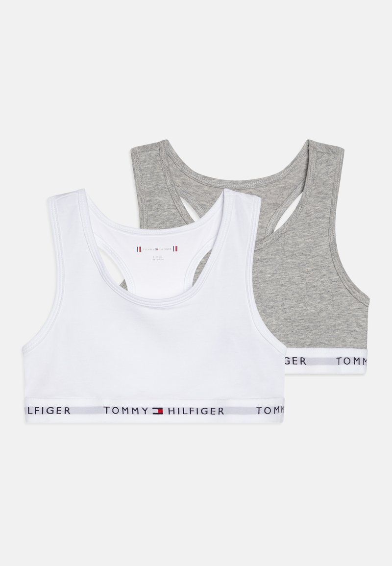 Dos sujetadores deportivos: uno blanco y uno gris. Ambos tienen un diseño de espalda de nadador y cuentan con una banda elástica con logo en colores contraste.