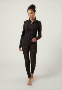 Ensemble de vêtements de sport en imprimé léopard dans des tons de noir et de brun. Veste zippée à manches longues avec des leggings ajustés assortis. Texture douce et extensible.