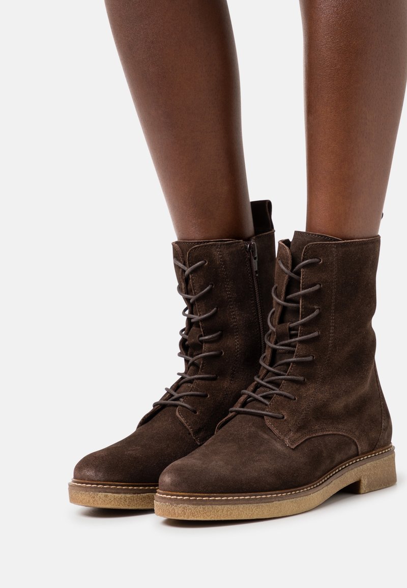 Stivaletti alla caviglia in suede marrone, con lacci davanti, chiusura con zip laterale, punta rotonda e suola in gomma texturizzata.