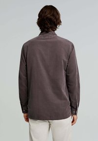 Dark gray corduroy shirt with long sleeves, button cuffs, and a straight hem. Features a classic collar and a soft texture.