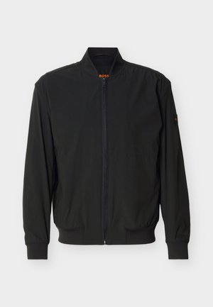 Μαύρο ελαφρύ bomber μπουφάν με κλείσιμο με φερμουάρ, ριμπ γιακά, μανσέτες και τελείωμα, και διακριτικό λογότυπο στον γιακά και το μανίκι.