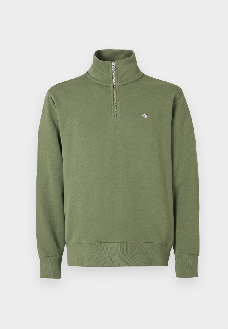Sudadera de color verde oliva con cuello con cremallera, confeccionada en tela suave, con mangas largas, puños acanalados y un pequeño logo bordado en el pecho.