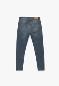 Dunkelblaue Denim-Jeans mit schmaler Passform, ausgestattet mit zwei Gesäßtaschen und einem braunen Lederpatch am Bund. Sauberer Abschluss am Saum.