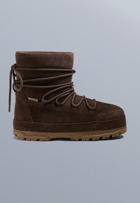 Barna bőrhatású bakancs magas szárú, vastag fűzőkkel, gumitalppal és texturált felülettel. Oldalán logó címkével és megerősített varrással rendelkezik.