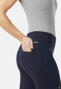 Leggings navy con vita alta, dotati di tasche e di un tessuto liscio ed elasticizzato. Il design include cerniere sulle tasche.