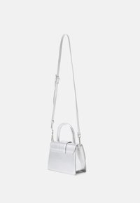 Sac à main métallisé en argent avec une bandoulière amovible, forme structurée, poignée supérieure et un détail de rabat. Texture lisse.
