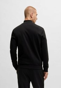 Zwarte sweatshirt met een hoge kraag, lange mouwen en geribde manchetten, met een gladde textuur en eenvoudig design.