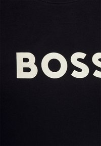 Sudadera negra con grandes letras blancas que dicen "BOSS". Hecha de tela suave con una textura lisa y un cuello redondo clásico.