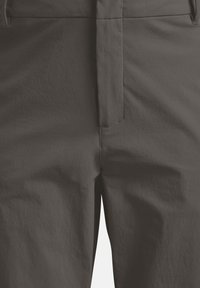 Primo piano di pantaloni grigio scuro che mostrano la zip frontale e i dettagli delle cuciture delle tasche su tessuto strutturato.