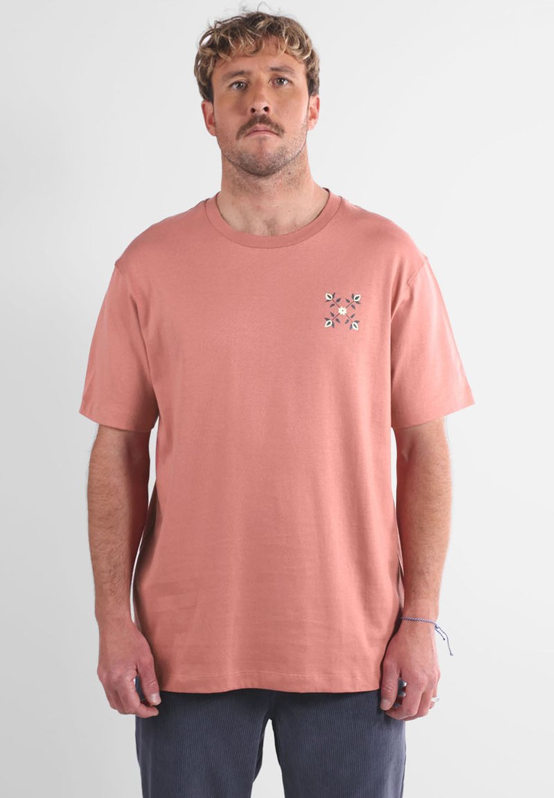 T-shirt en coton corail à manches courtes, avec un col ras-du-cou et un petit design de broderie florale sur la poitrine gauche. Coupe décontractée, texture douce.