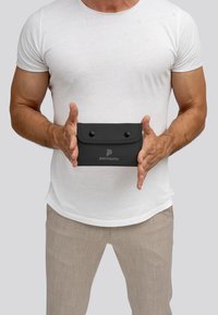 Zwarte, rechthoekige pouch gemaakt van synthetisch materiaal, met twee drukknoopknopen en een logo in het midden. Vashand tegen een grijze achtergrond.