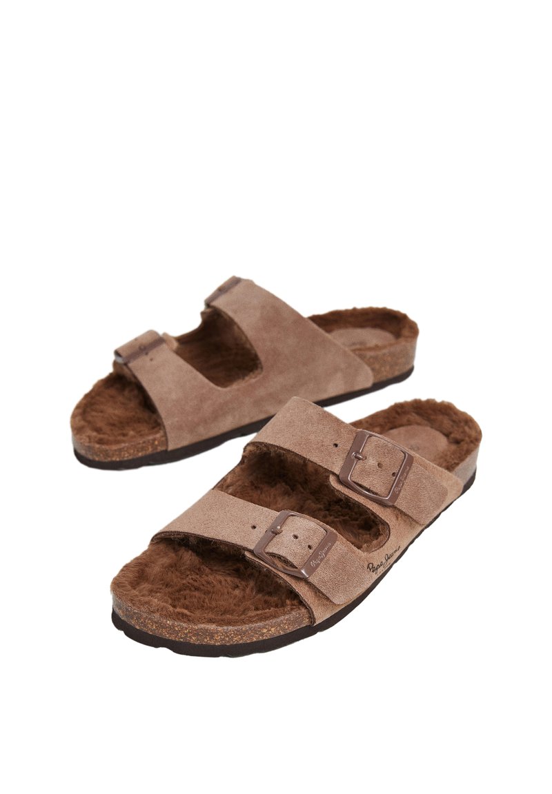 Braune Wildledersandalen mit zwei verstellbaren Riemen, weichem Fellfutter und einer strukturierten braunen Außensohle. Schnallen verleihen dem Design zusätzliche Details.