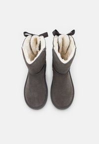 Bottes cheville en suède gris avec doublure en fausse fourrure blanche douce, bouts arrondis et accents de ruban noir en haut. Semelles plates.