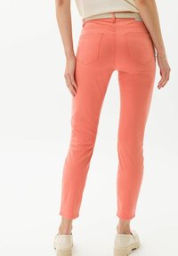 Różowe skinny jeans z koralu wykonane z mieszanki bawełny, z tylnymi kieszeniami i paskiem w talii, stylizowane z jasnymi, grubymi butami.