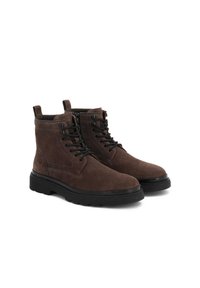 Botas de tobillo de ante marrón con cordones negros, punta redonda, suela de goma resistente y dos tiradores en la parte superior para facilitar su calzado.