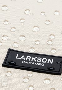 Water-resistant beige fabric with circular water droplets, featuring a black rectangular label with white text: "LARKSON HAMBURG."