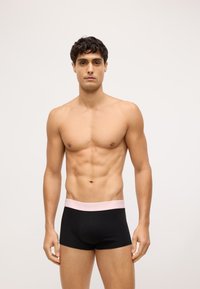 Čierne bavlnené boxerky s elastickým pásom svetloružovej farby s logom "Calvin Klein". Hladká textúra, priliehavý strih.